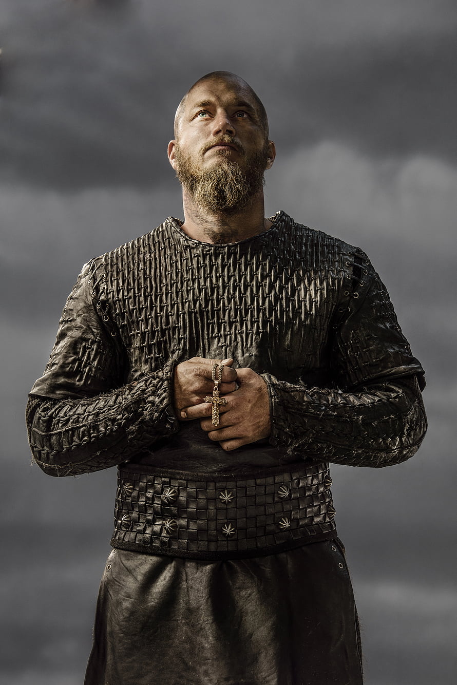 Ragnar Lothbrok in Viking Armor Holding a Cross Against a Stormy Sky HD phone wallpaper