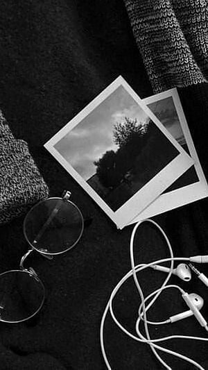Monochrome Flat Lay With Polaroid Photos, Round Glasses, and Wired Earbuds on Dark Fabric HD phone wallpaper