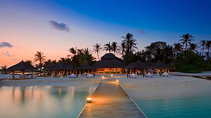 Luxury Overwater Beach Resort at Sunset with Thatched Cabanas and Wooden Walkway HD wallpaper