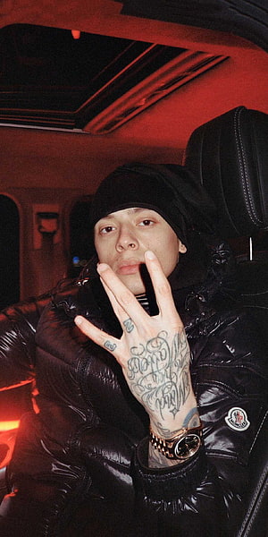Central Cee in a black puffer jacket with hand tattoos and a gold watch inside a car with red lighting HD phone wallpaper