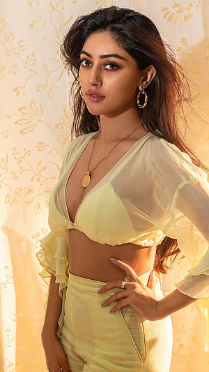Adah Sharma in a stylish yellow two-piece outfit with sheer blouse and high-waisted pants posing against a floral background HD phone wallpaper
