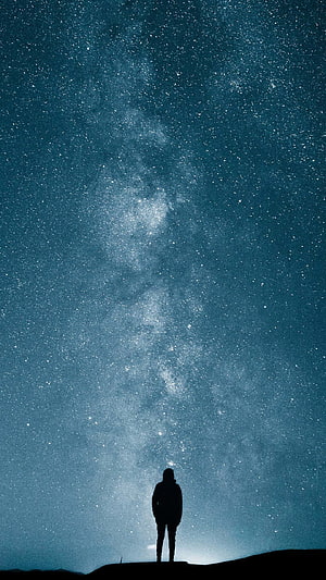Silhouette of a Lone Figure Standing Beneath the Milky Way Galaxy at Night HD phone wallpaper
