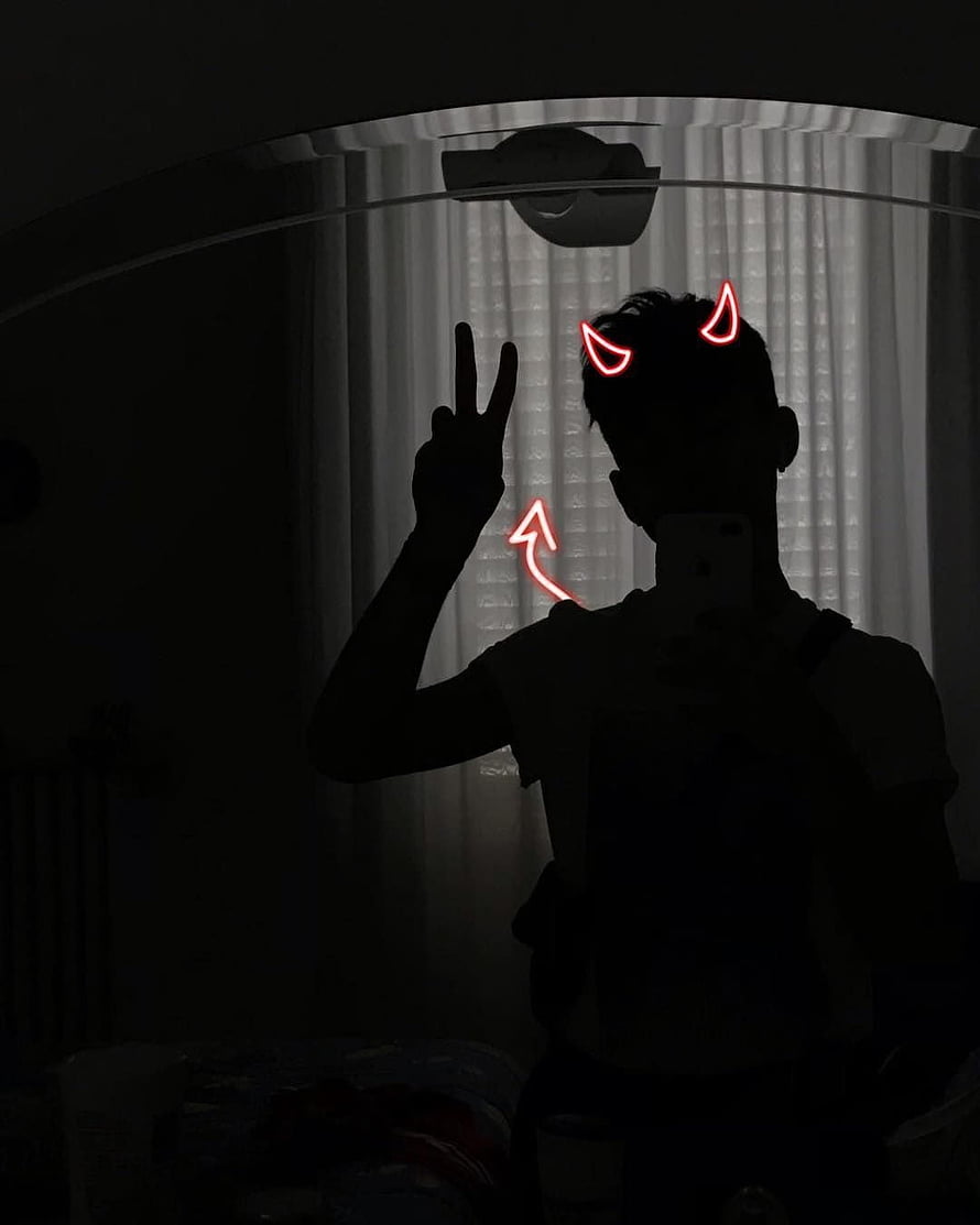 Silhouette of a person making a peace sign with red neon devil horns and arrow doodles in a dark room HD phone wallpaper