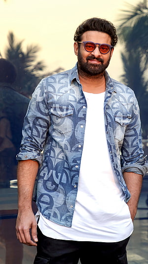Prabhas in a stylish patterned denim shirt and sunglasses posing outdoors HD phone wallpaper