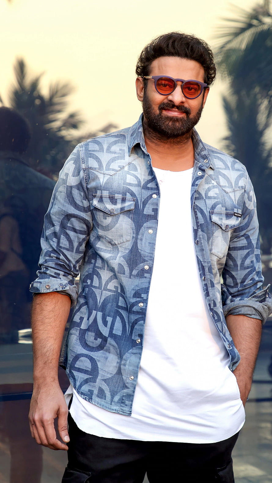 Prabhas in a stylish patterned denim shirt and sunglasses posing outdoors HD phone wallpaper