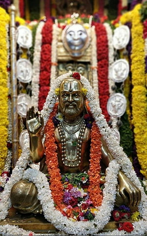 Golden Statue of Sai Baba Adorned with Flower Garlands and Silver Medals HD phone wallpaper