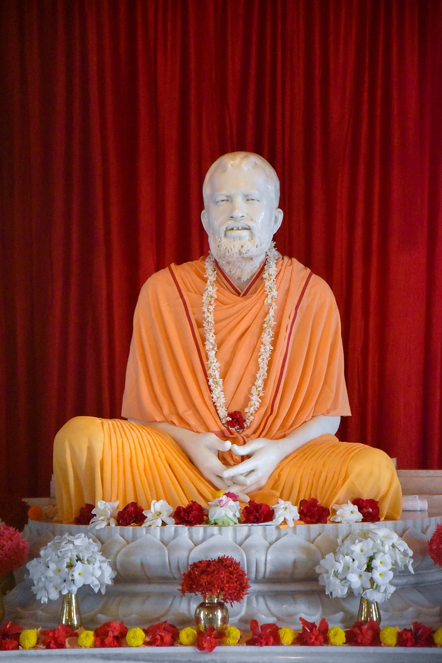 White Statue of Swami Vivekananda in Orange Robes with Flower Offerings HD phone wallpaper