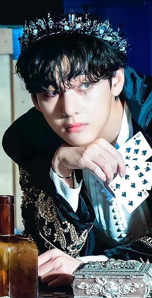 V from BTS wearing a jeweled crown and holding playing cards in a dark fantasy portrait HD phone wallpaper