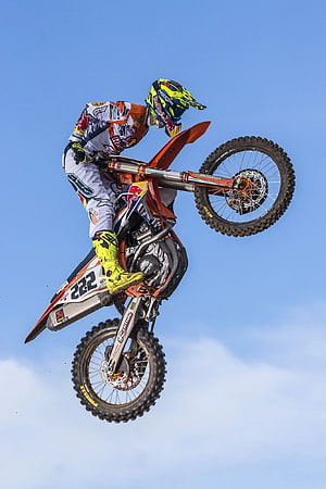 Tony Cairoli mid-air on a KTM dirt bike during a motocross jump against a clear blue sky HD phone wallpaper