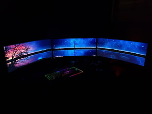 Triple Monitor Setup With Curved Ultrawide Displays and RGB Keyboard in a Dark Room HD wallpaper