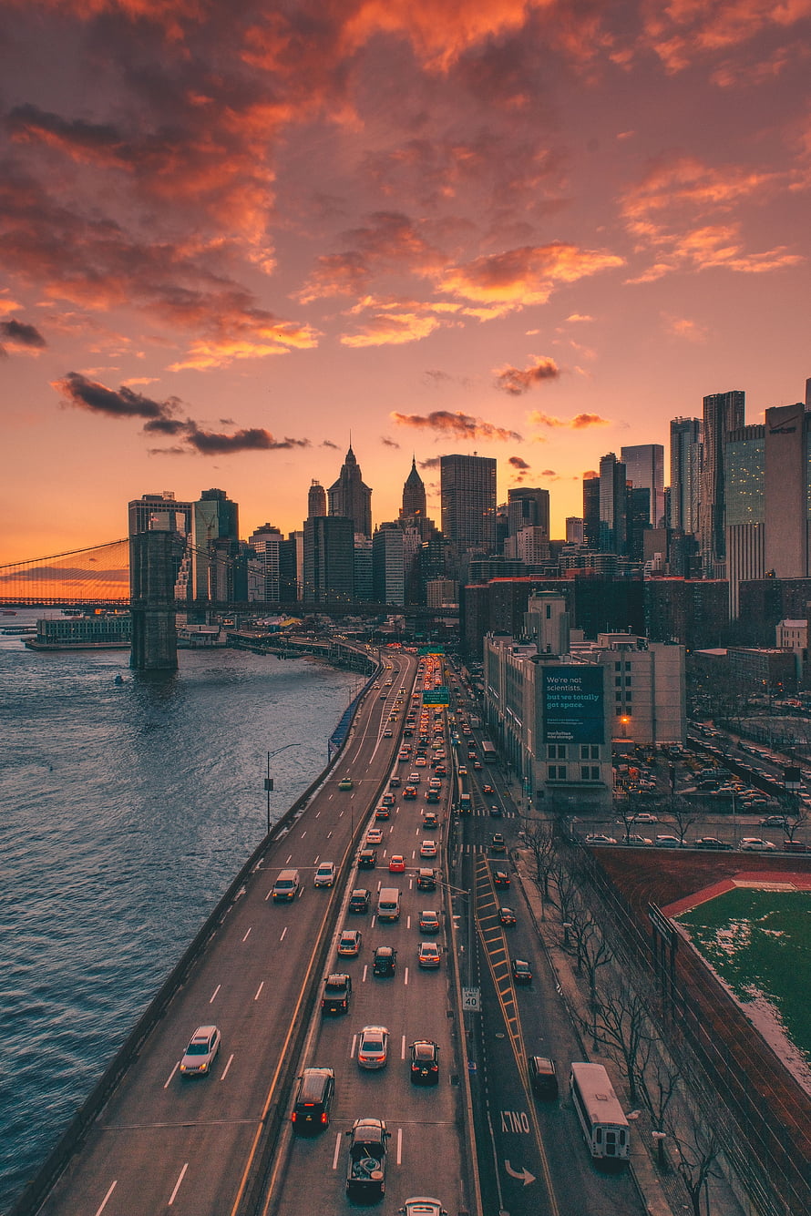 Aerial View of Manhattan Skyline and Brooklyn Bridge at Sunset with Busy Highway Traffic HD phone wallpaper