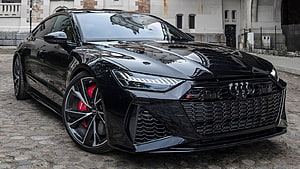 Black Audi RS7 Sportback with Red Brakes Parked on Cobblestone Street HD wallpaper