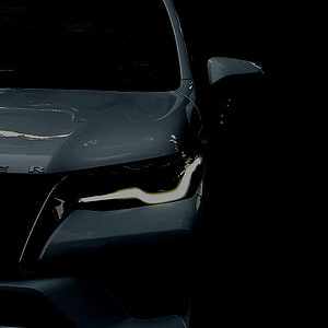 Close-up of a sleek dark grey car headlight with LED daytime running lights in a moody low-light setting HD phone wallpaper