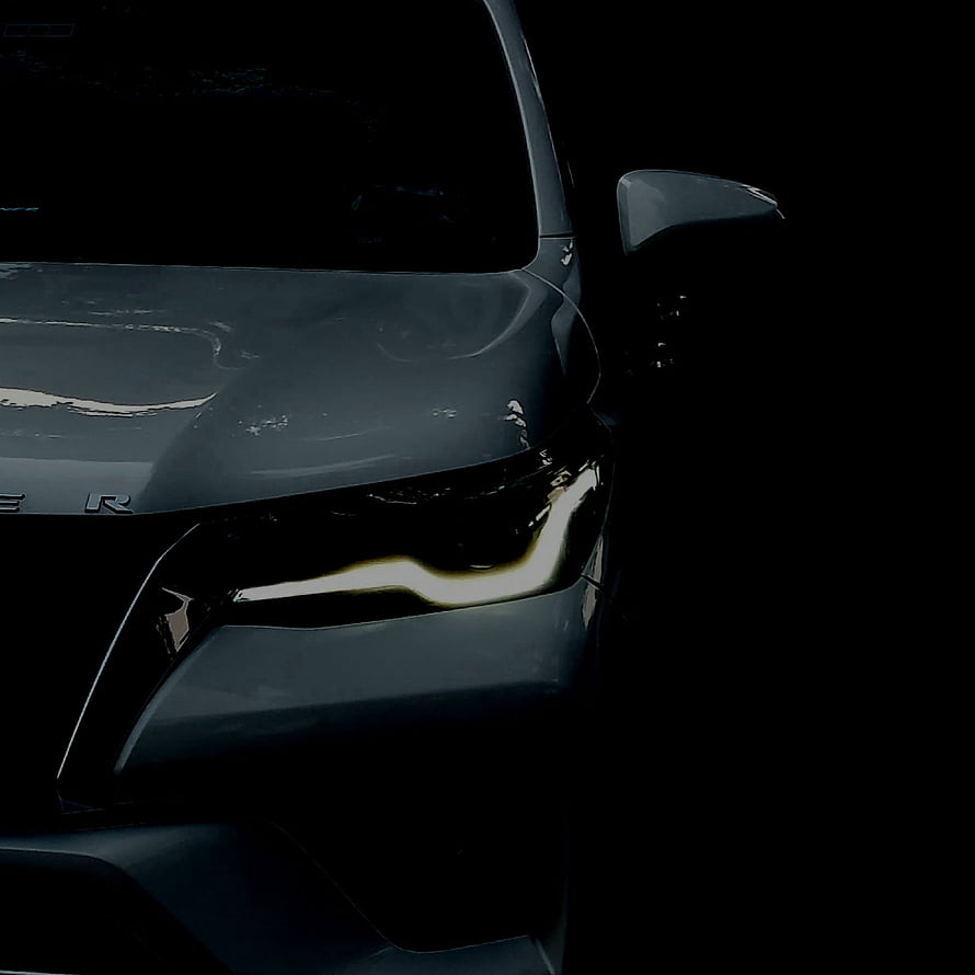 Close-up of a sleek dark grey car headlight with LED daytime running lights in a moody low-light setting HD phone wallpaper