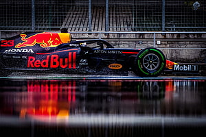 Red Bull Racing Formula 1 car speeding on wet track with vibrant reflection HD wallpaper