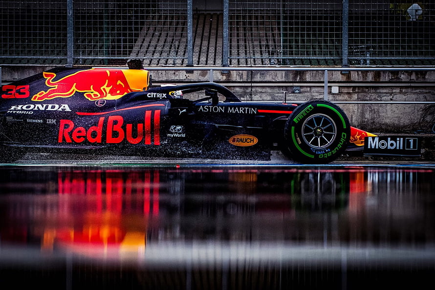 Red Bull Racing Formula 1 car speeding on wet track with vibrant reflection HD wallpaper