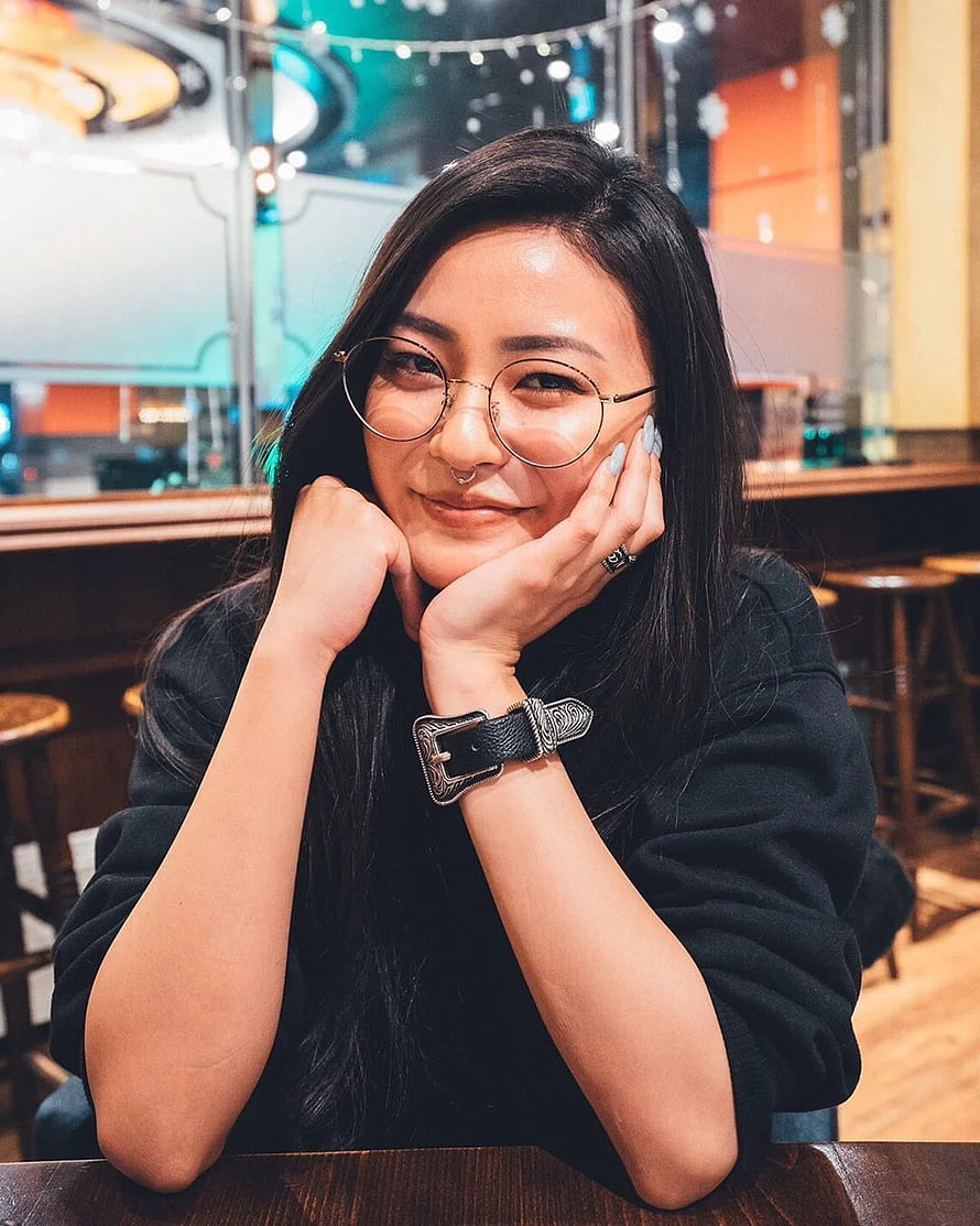Portrait of a smiling woman with glasses and a nose ring resting her chin on her hands in a cafe, Rae Lil Black HD phone wallpaper