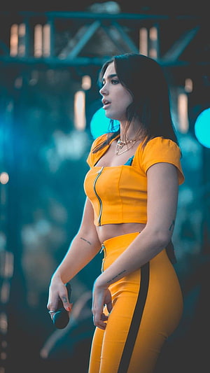 Dua Lipa in a vibrant yellow two-piece stage outfit performing under cool blue concert lighting HD phone wallpaper