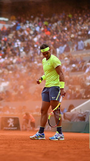 Rafael Nadal on the red clay court at Roland Garros in a neon yellow Nike kit HD phone wallpaper