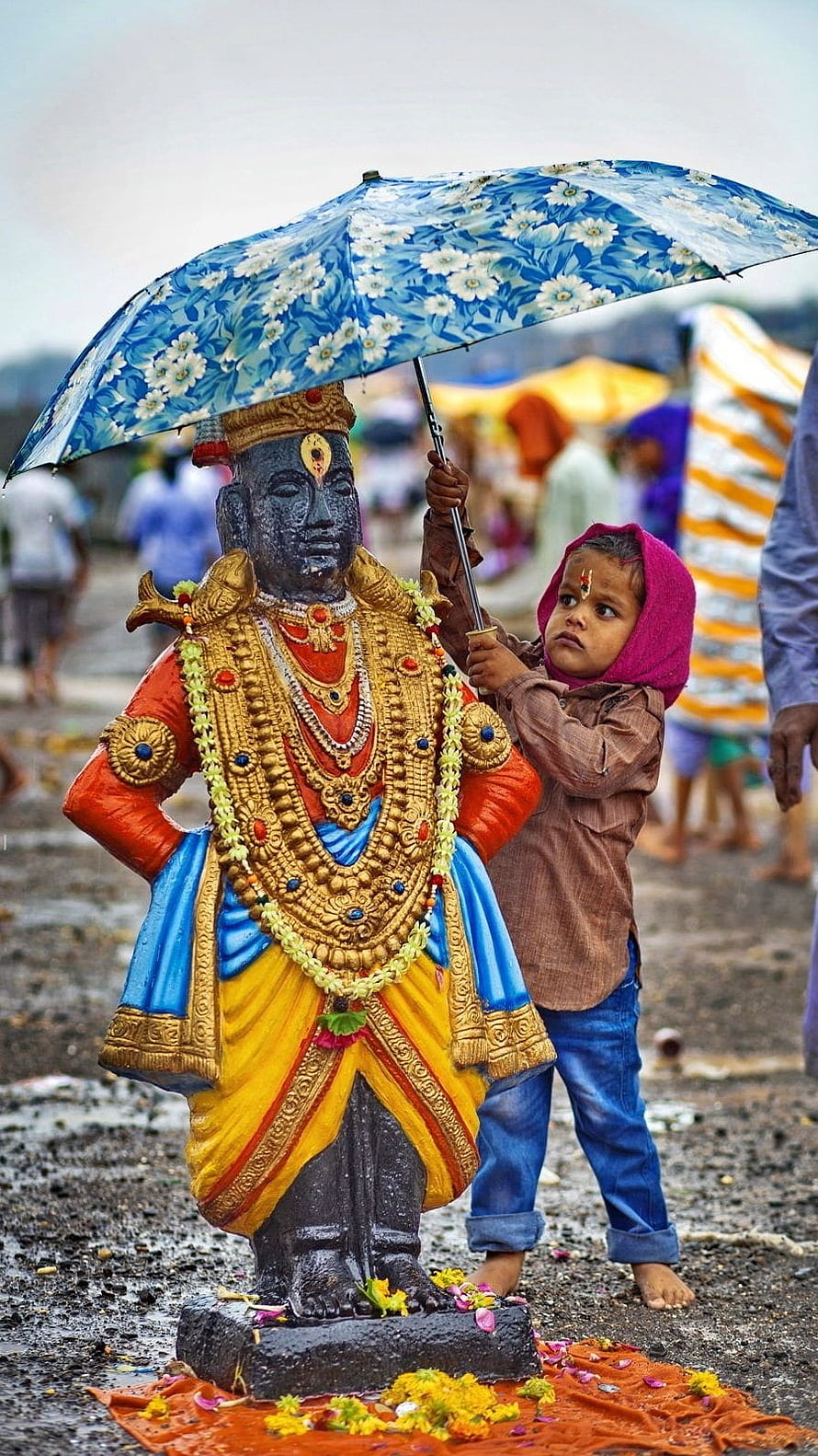 Young Boy Holding Umbrella Over Ornate Vitthal Statue at Outdoor Festival HD phone wallpaper