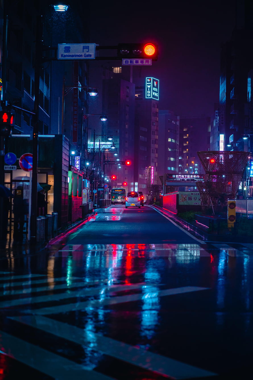 Neon-lit Tokyo street at night with wet pavement reflecting vibrant city lights HD phone wallpaper