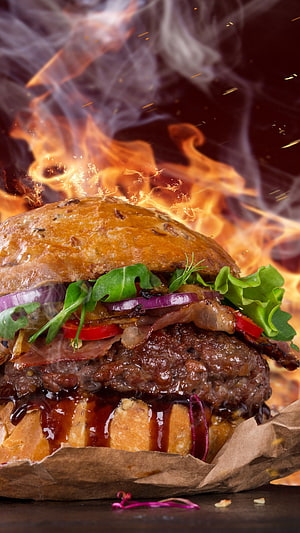 Flaming Gourmet Burger With Crispy Bacon, Fresh Greens, and Melted Cheese on a Dark Background HD phone wallpaper