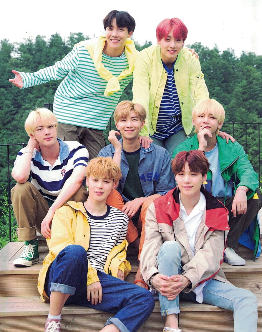 BTS K-pop group members posing together outdoors in colorful casual streetwear on wooden steps HD phone wallpaper