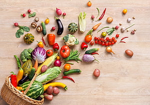 Fresh Organic Vegetables Spilling From Wicker Basket On Wooden Table HD wallpaper