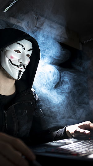 Anonymous Guy Fawkes Mask Hacker Typing on Laptop in Dramatic Blue Smoke HD phone wallpaper