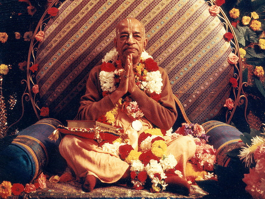 Srila Prabhupada Seated in Prayer with Flower Garlands and Sacred Text HD wallpaper