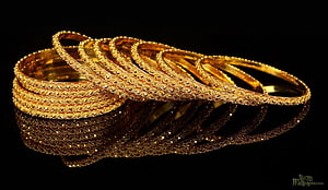 Intricate Gold Bangle Bracelets with Filigree Patterns on Black Background HD wallpaper