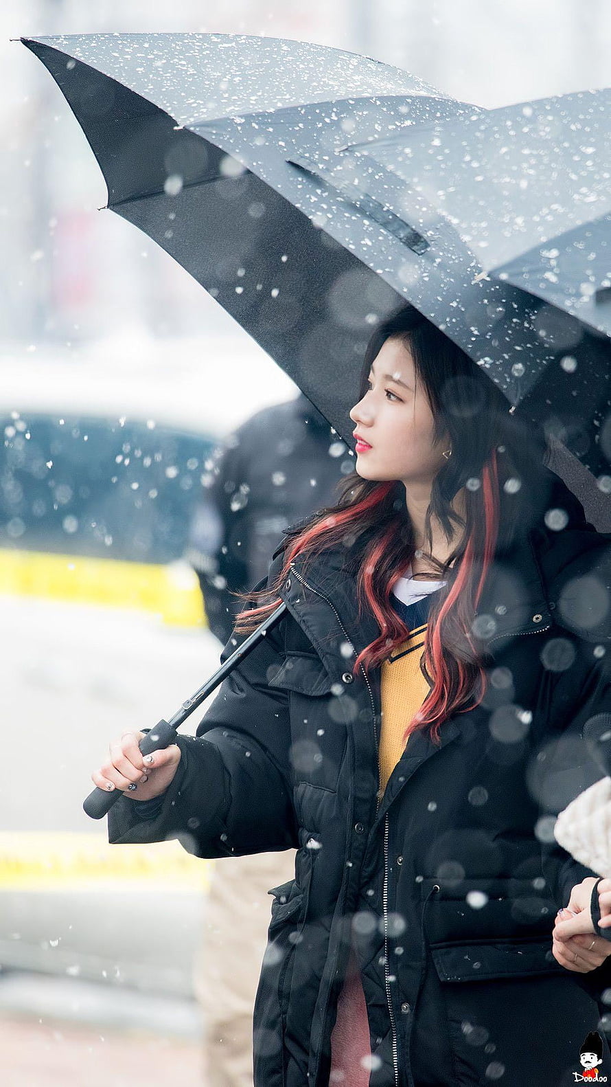 Sana from TWICE holding a black umbrella in falling snow with red-streaked hair and a winter coat HD phone wallpaper