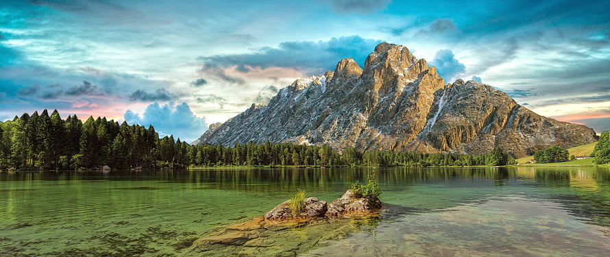 Serene Alpine Lake with Rocky Outcrop and Majestic Mountain Peak HD wallpaper