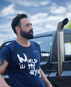 Babbu Maan in a navy graphic t-shirt standing beside a black SUV under a cloudy sky HD phone wallpaper