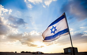 Israeli Flag Waving Over Desert Military Base at Golden Hour Sunset HD wallpaper