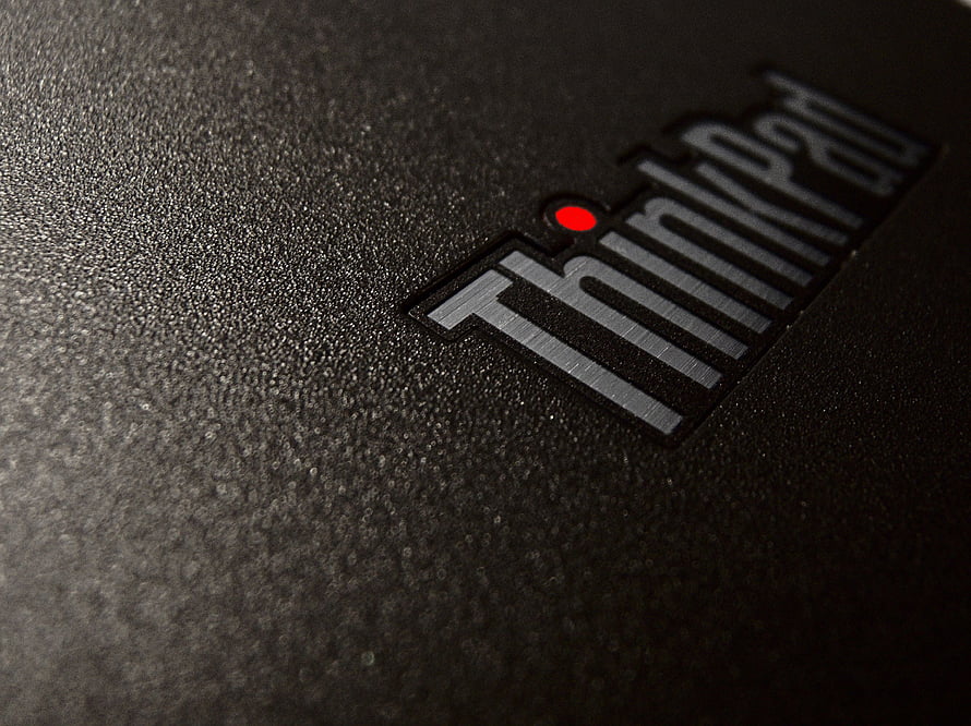 Close-up of the ThinkPad logo on a textured black laptop lid with a red dot accent HD wallpaper