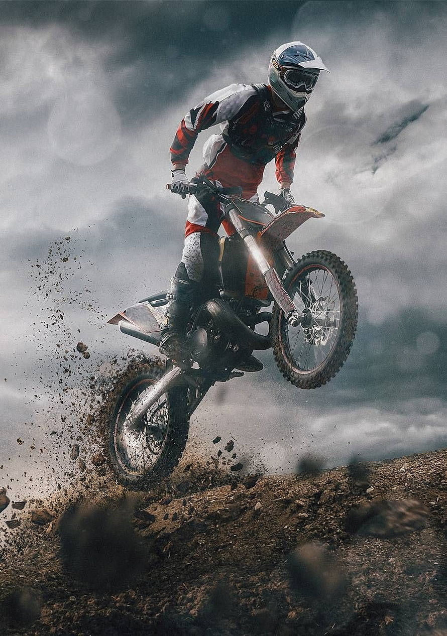 KTM Dirt Bike Rider Launching Off a Muddy Trail Under a Dramatic Stormy Sky HD phone wallpaper