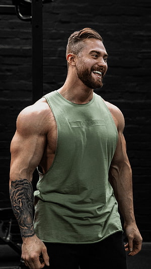 Chris Bumstead in Green Gym Tank Top with Tiger Arm Tattoo in Dark Studio HD phone wallpaper