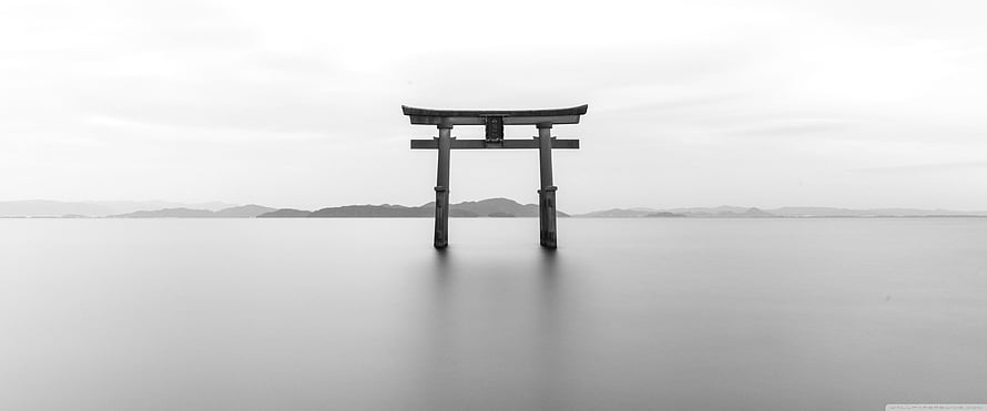 Monochrome Torii Gate Standing in Calm Water with Distant Mountains HD wallpaper