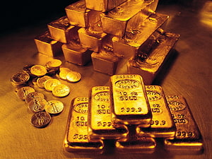 Stacked Gold Bars and Scattered Coins on a Reflective Surface HD wallpaper