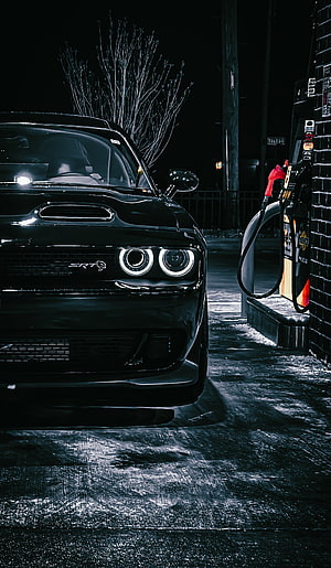 Black Dodge Challenger SRT parked at a gas station at night with glowing headlights HD phone wallpaper