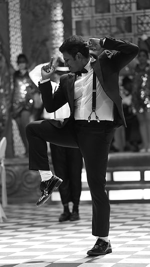 Puneeth Rajkumar in a dynamic dance pose wearing a tuxedo and suspenders on a checkered floor HD phone wallpaper