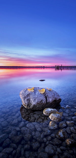 Serene Lake Sunset With Large Rock And Yellow Leaves In Foreground HD phone wallpaper