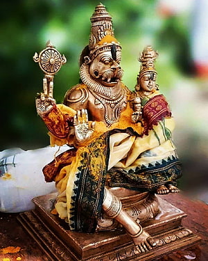 Traditional brass statue of Lord Yama holding a danda with his consort, adorned in vibrant yellow and green silk garments HD phone wallpaper