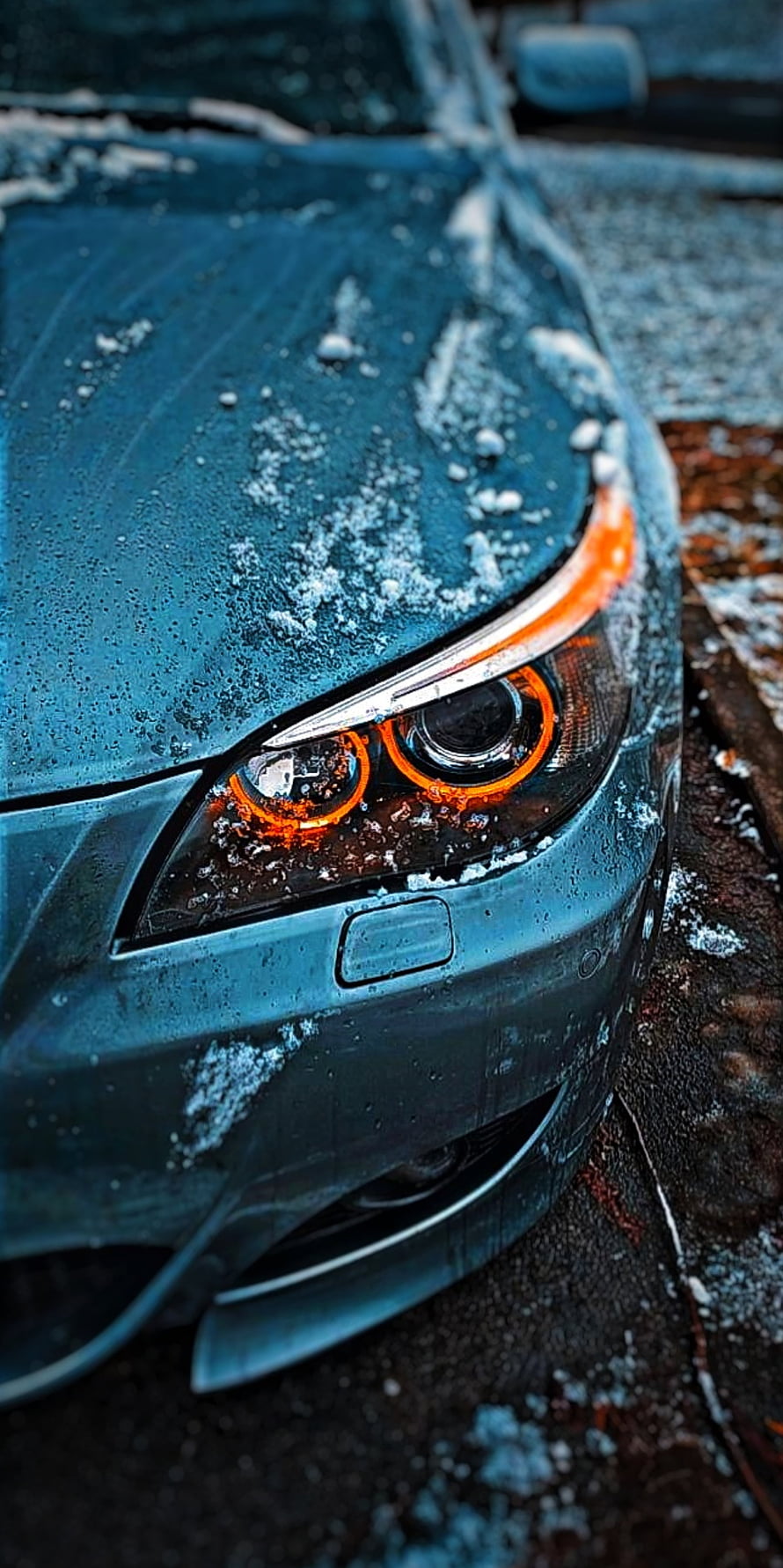 Close-up of a BMW E60 M5 headlight with glowing orange rings on a frosty winter morning HD phone wallpaper