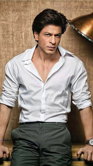 Shah Rukh Khan in a white shirt and dark trousers posing with an intense expression HD phone wallpaper