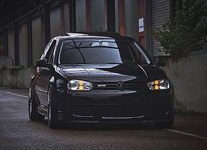 Black Volkswagen Golf Mk4 GTI parked on a wet street with amber turn signals illuminated HD wallpaper