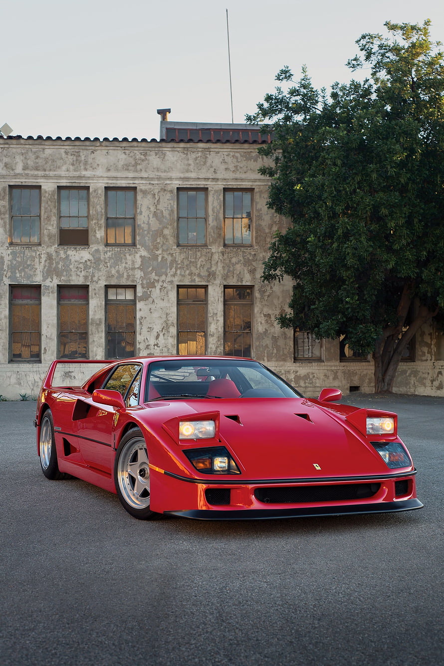 Red Ferrari F40 Super Car Parked in Front of Weathered Industrial Building HD phone wallpaper