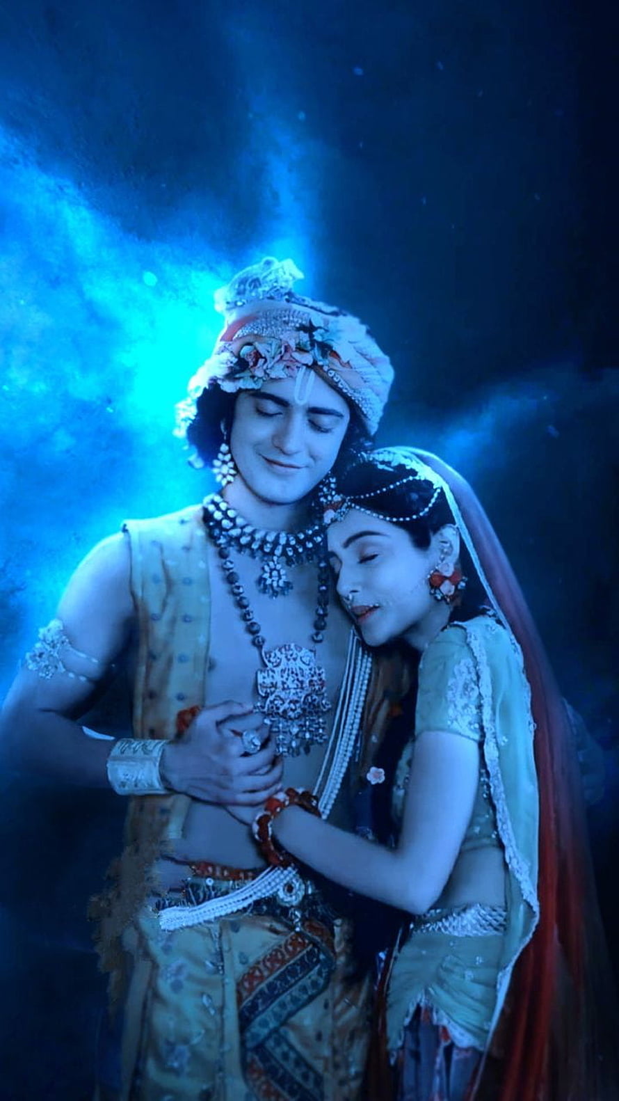 Radha and Krishna embracing in traditional attire with blue lighting HD phone wallpaper
