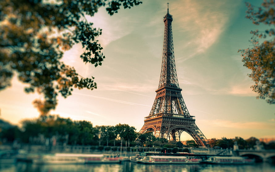 Eiffel Tower at Sunset Over the Seine River in Paris with Soft Golden Light and Framing Trees HD wallpaper